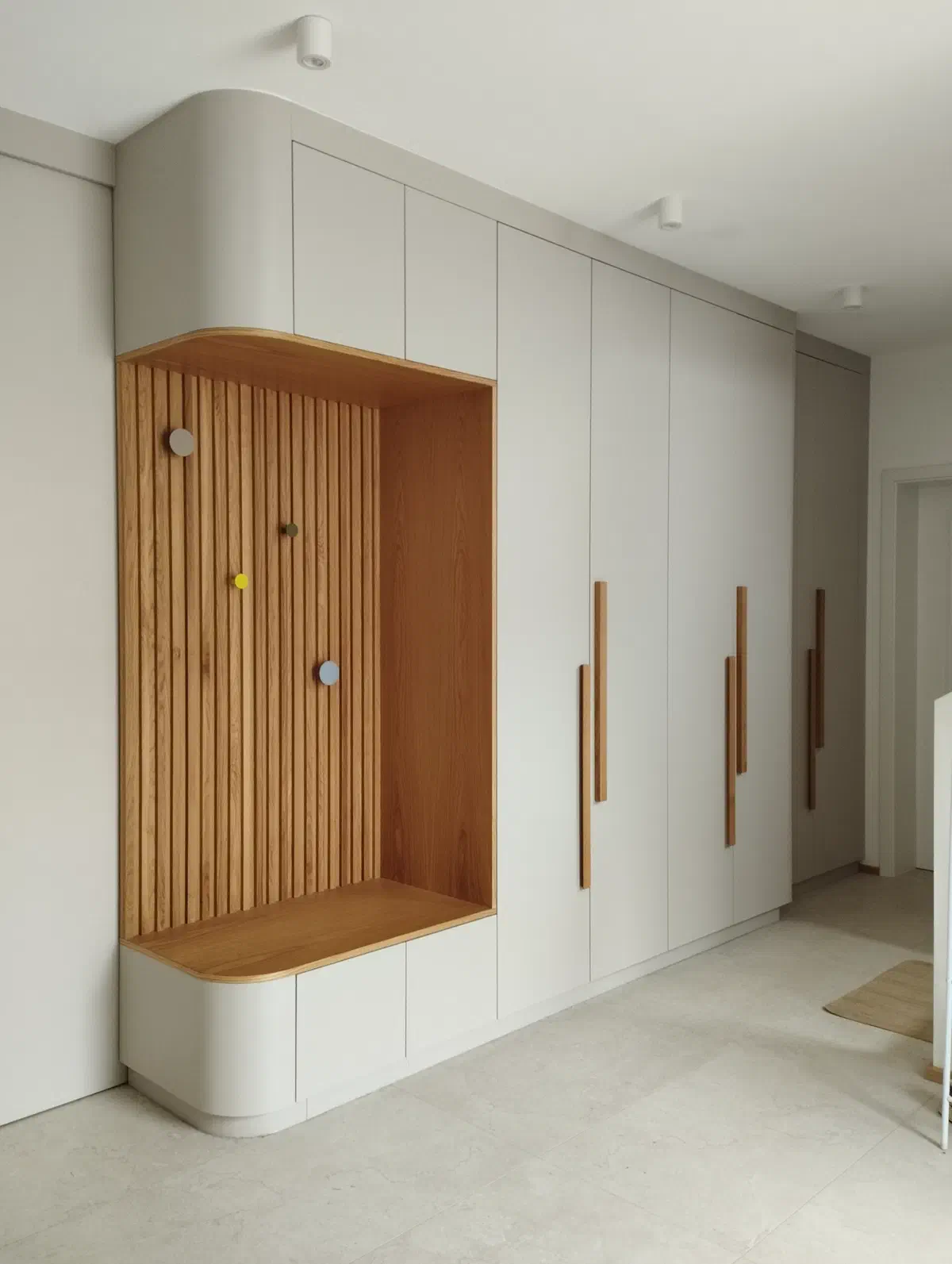 Einbauwand vom Tischler mit Holznische, Lamellen, Sitzbank und grifflosen Fronten