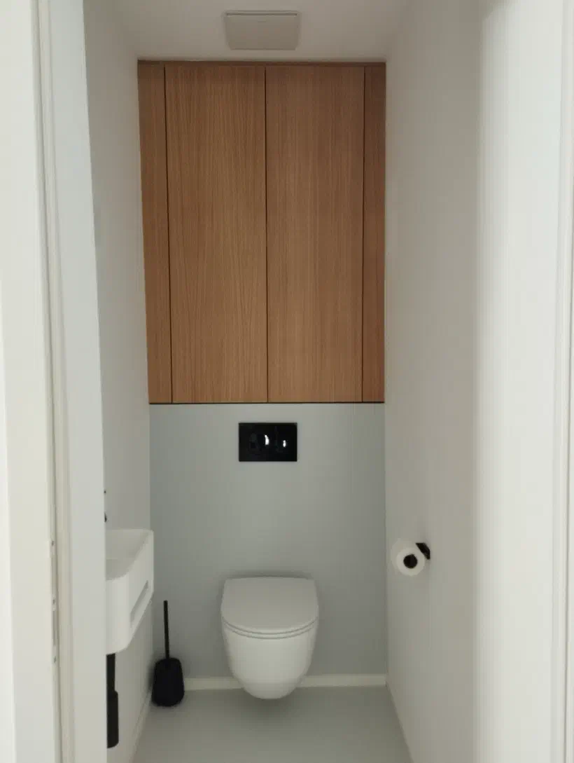 Schmaler WC-Raum mit deckenhohem Hängekasten und grifflosen Holzfronten über dem Hänge-WC