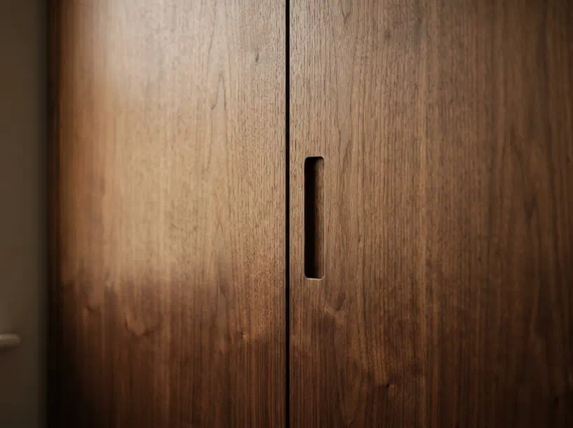 Einbauschrank mit flächenbündigen Fronten aus Nussholz und Griffmulde (KI-generiertes Bild)